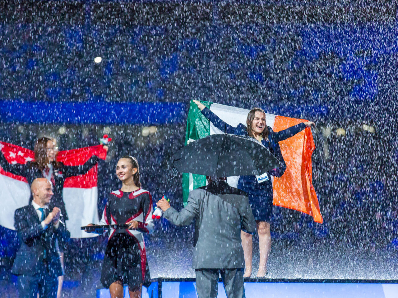 Megan Yeates celebrates on stage holding an Irish flag above her head after becoming a Freight Forwarding Champion and gold Medallist at WorldSkills Kazan 2019.